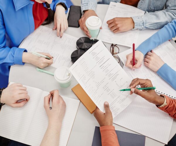 Top view of table with notebooks and documents busy group of college students preparing for exams